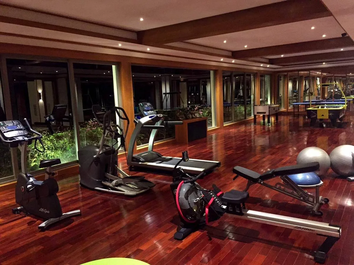 A home gym with a treadmill, exercise bike, rowing machine and free weights on a wood floor