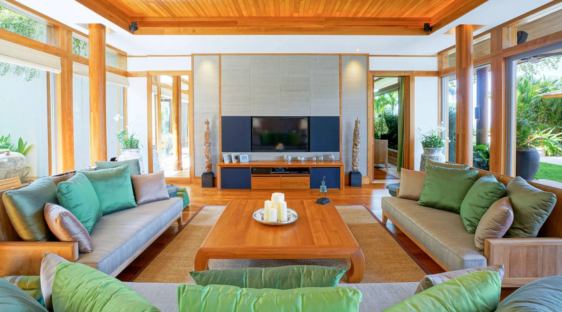 A living room with green cushioned sofas, a wood coffee table and a wall-mounted television