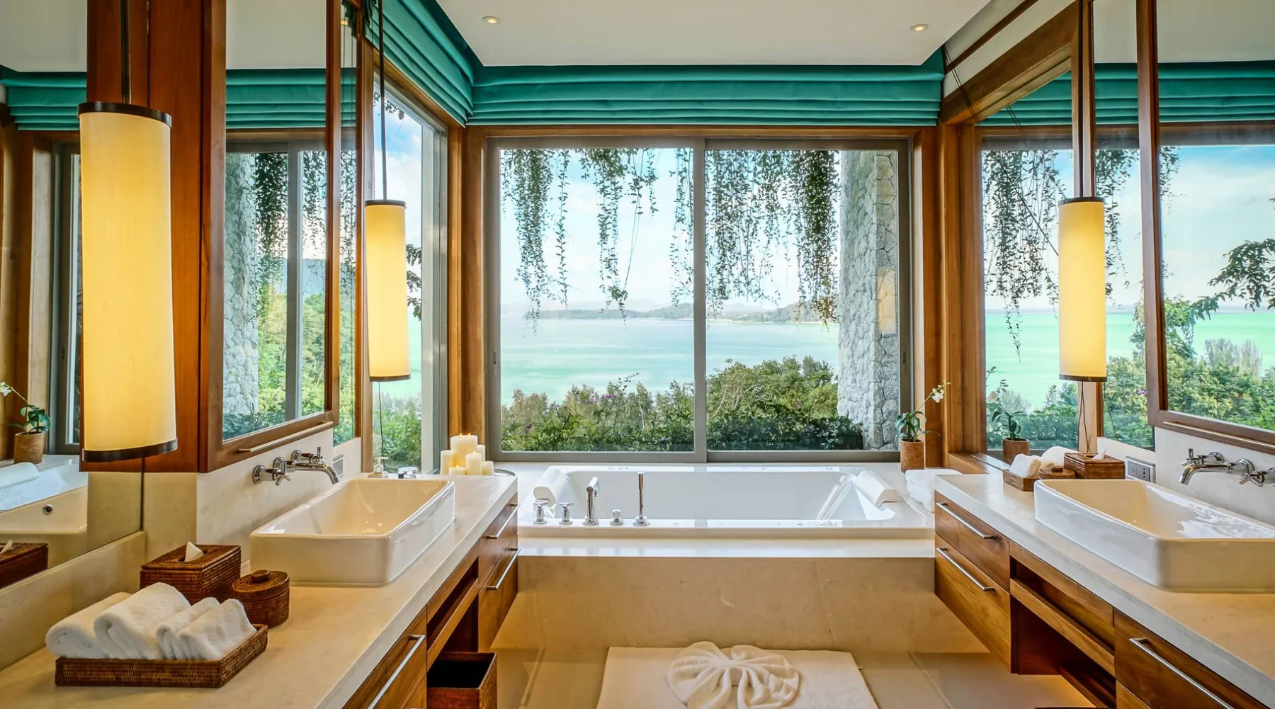 A bathroom with a double vanity and a large soaking tub set in front of floor to ceiling windows with a garden view