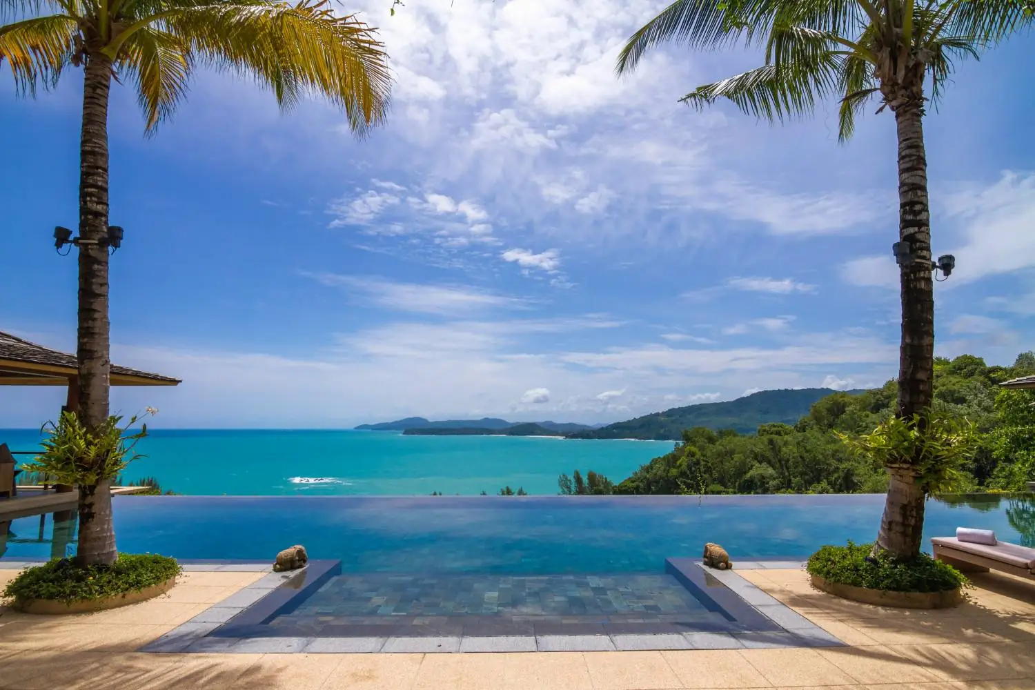 Infinity pool framed by twin palms with views over Kamala Bay