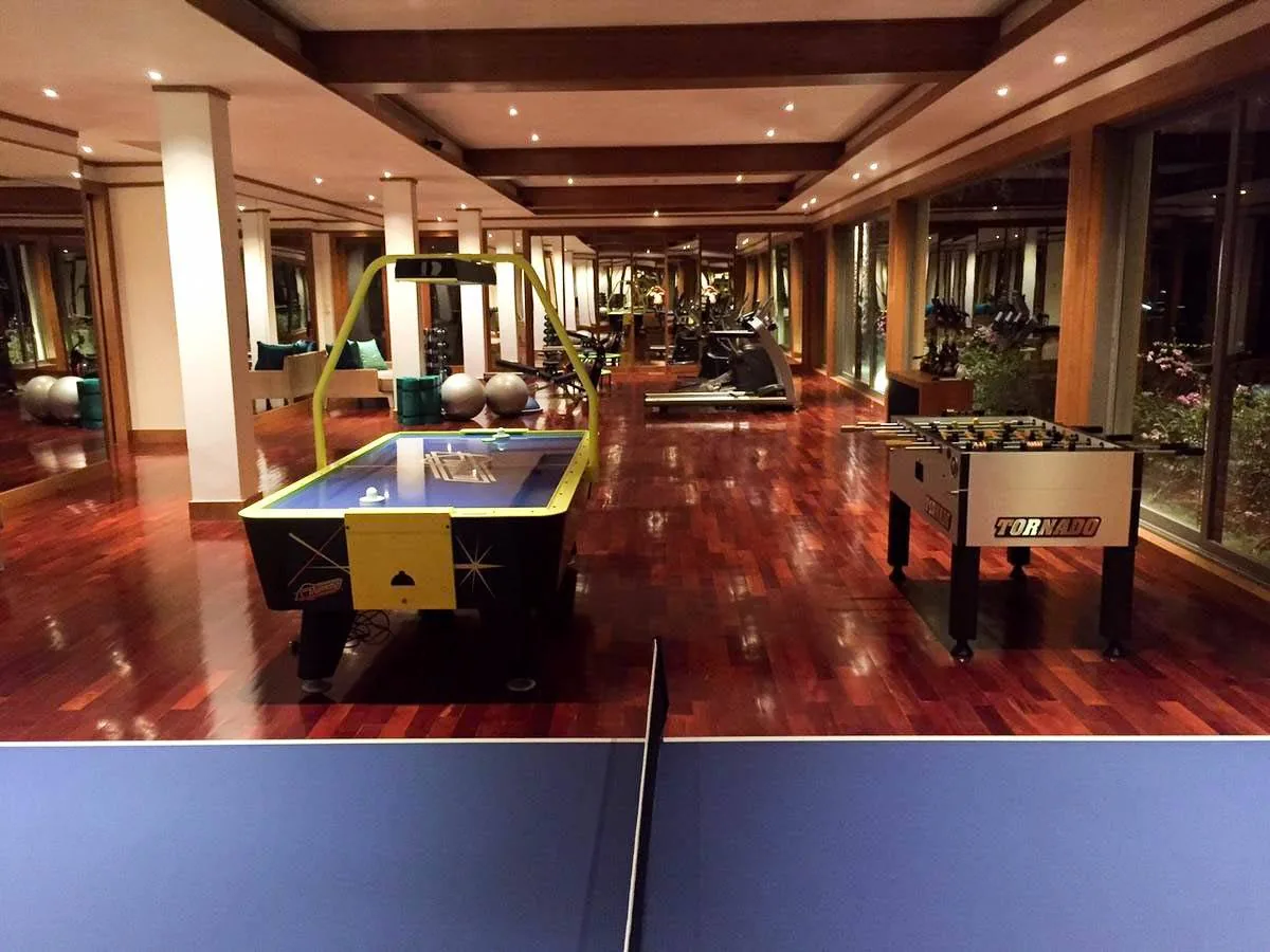 A games room with an air hockey table and a table football table on wood flooring