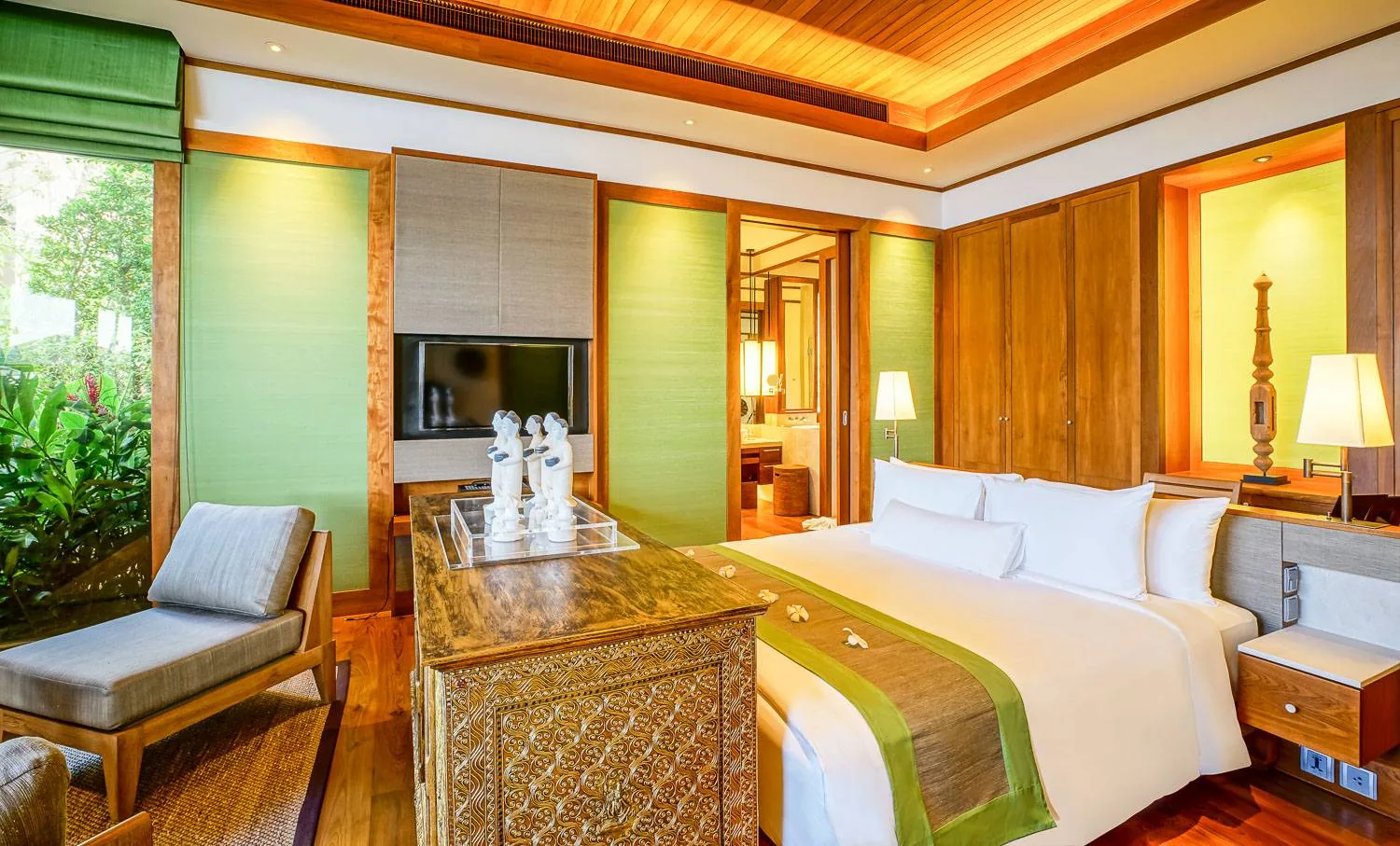 A bedroom with a patterned bedhead panel and a bed made up with white and green linen