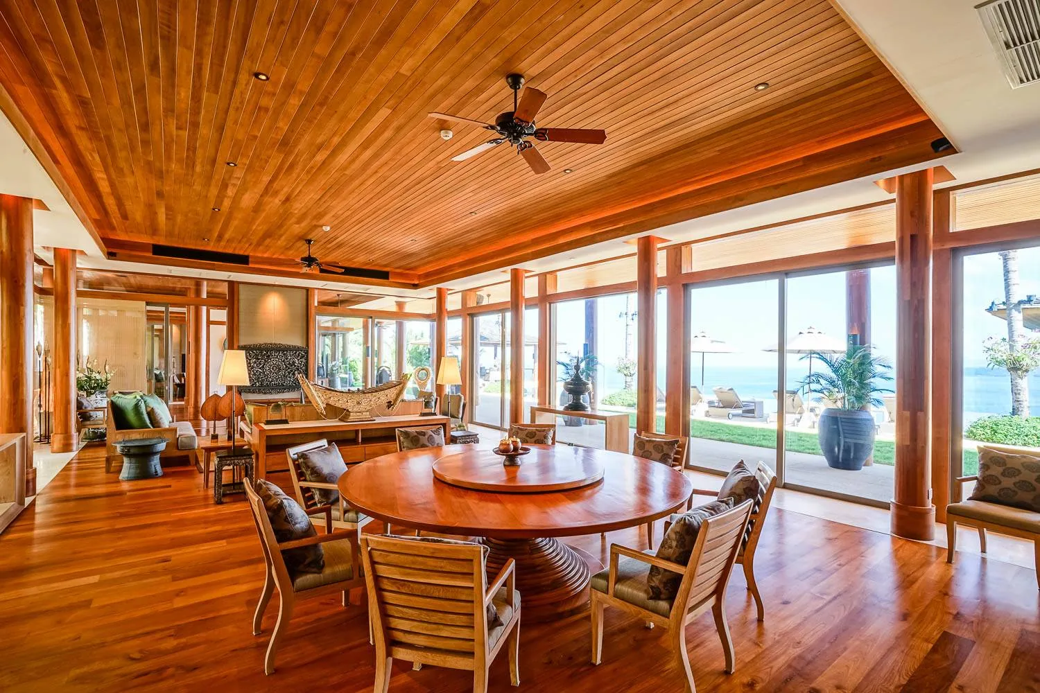 A dining area with a round wood table and chairs, under a wood ceiling