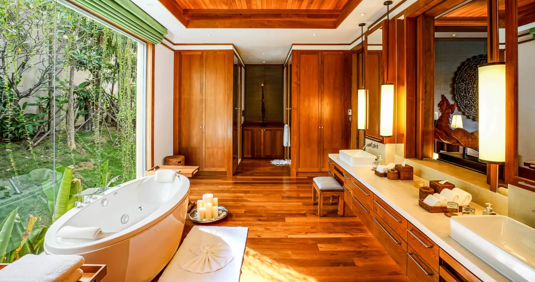 A bathroom with a round soaking tub, folded towels and timber cabinetry