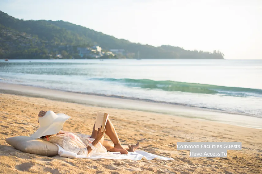 A person lying on a towel on a sandy beach; a caption in the corner reads Common Facilities Guests Have Access To