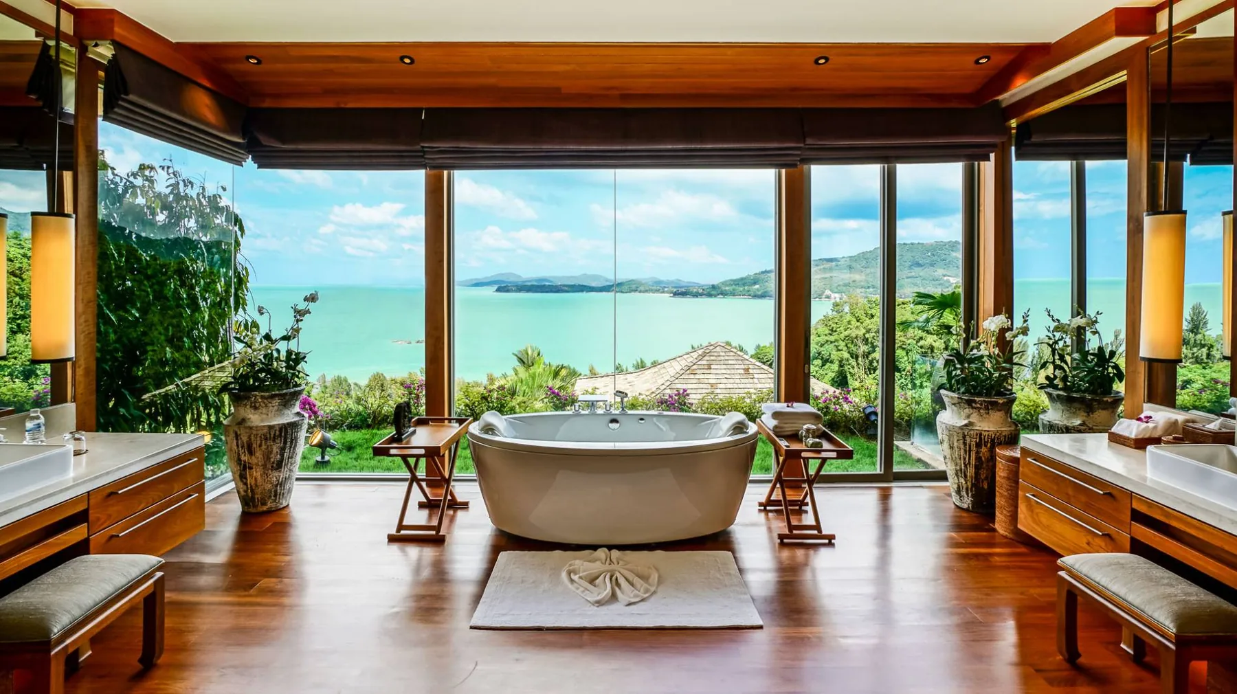 A bathroom with a freestanding tub set in front of floor to ceiling windows with a sea view
